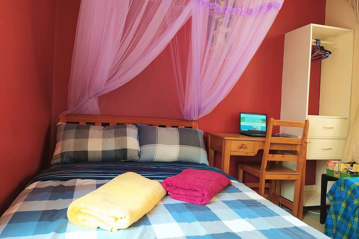 Ein Schlafzimmer mit einem Bett, einem Schreibtisch mit einem Laptop und einem Kleiderschrank.