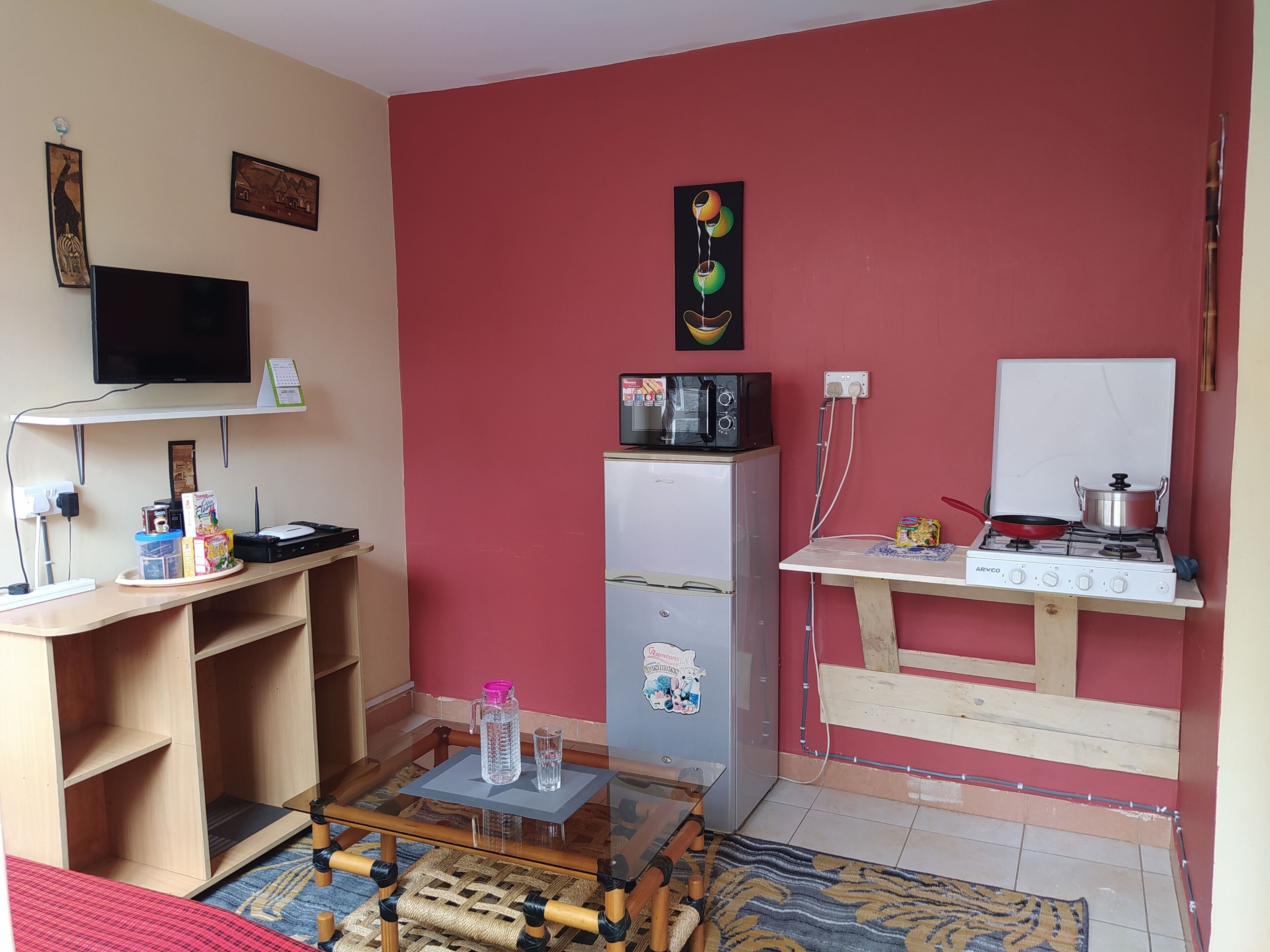 A compact living space with a kitchenette, a television, a refrigerator, and a small dining table.