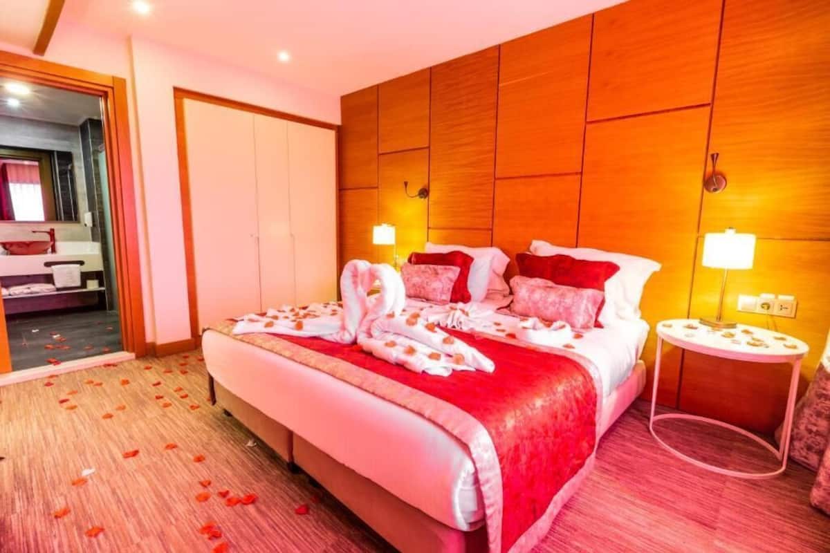 Een hotelkamer met een groot bed, een houten hoofdbord, een nachtkastje en een spiegel.