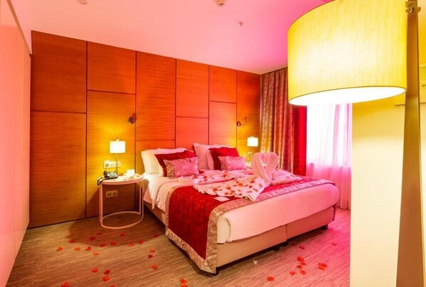 A hotel room with a large bed, a bedside table with a lamp, and a wall panel design. - Kuhla Hotel (Yomra)