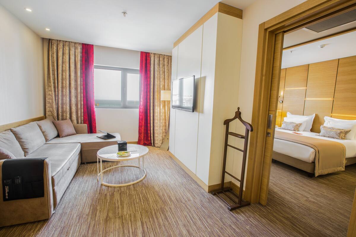 Hotelkamer met een bank, een klein rond tafeltje, een bed en een televisie.
