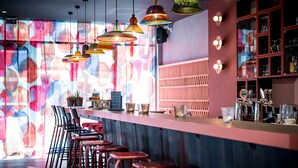 A bar area with multiple stools, hanging pendant lights, and shelves with glassware. - BOMA easy living hotel By Stay Collection (Strasbourg)
