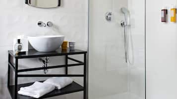 A modern bathroom with a glass-enclosed shower, a white sink with a black countertop, and a mirror above the sink.