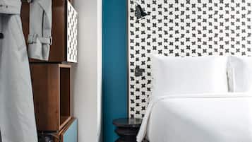 Una habitación de hotel con cama, armario de madera y perchero.
