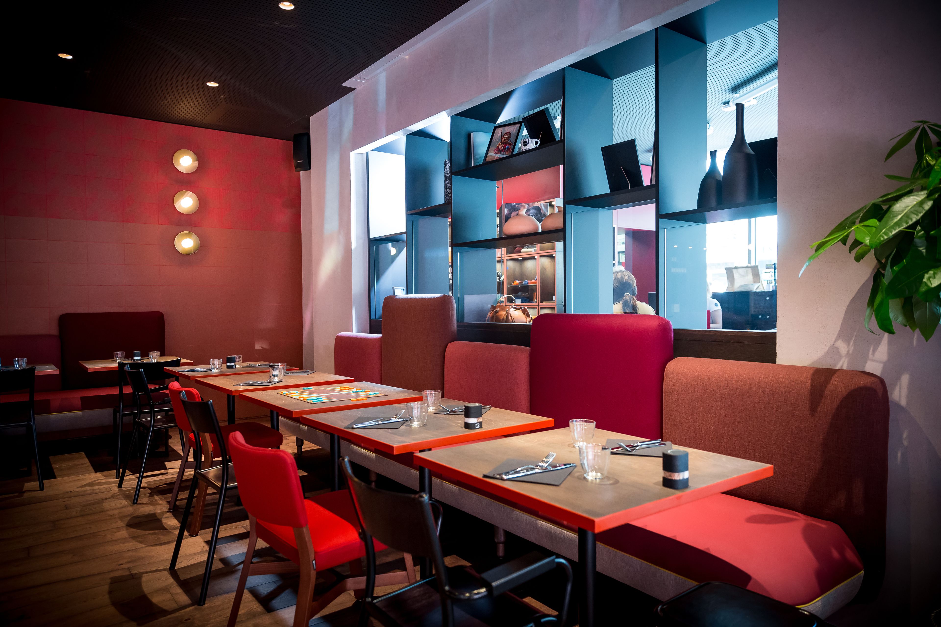 A restaurant with red and blue decor, wooden tables, and chairs.