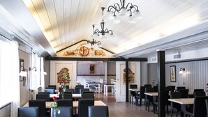 Un restaurant doté d’un plafond haut, de lustres et d’une arche décorative centrale. Les tables et les chaises sont disposées pour accueillir les clients.