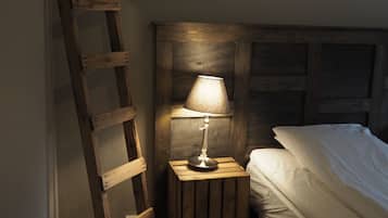 A wooden ladder leaning against a wall, a small wooden nightstand with a lamp, and a bed with white bedding.