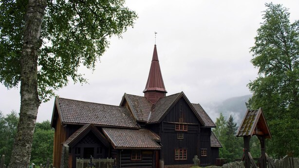 Une église traditionnelle en bois, dotée d’un toit à forte pente et d’un clocher rouge imposant.