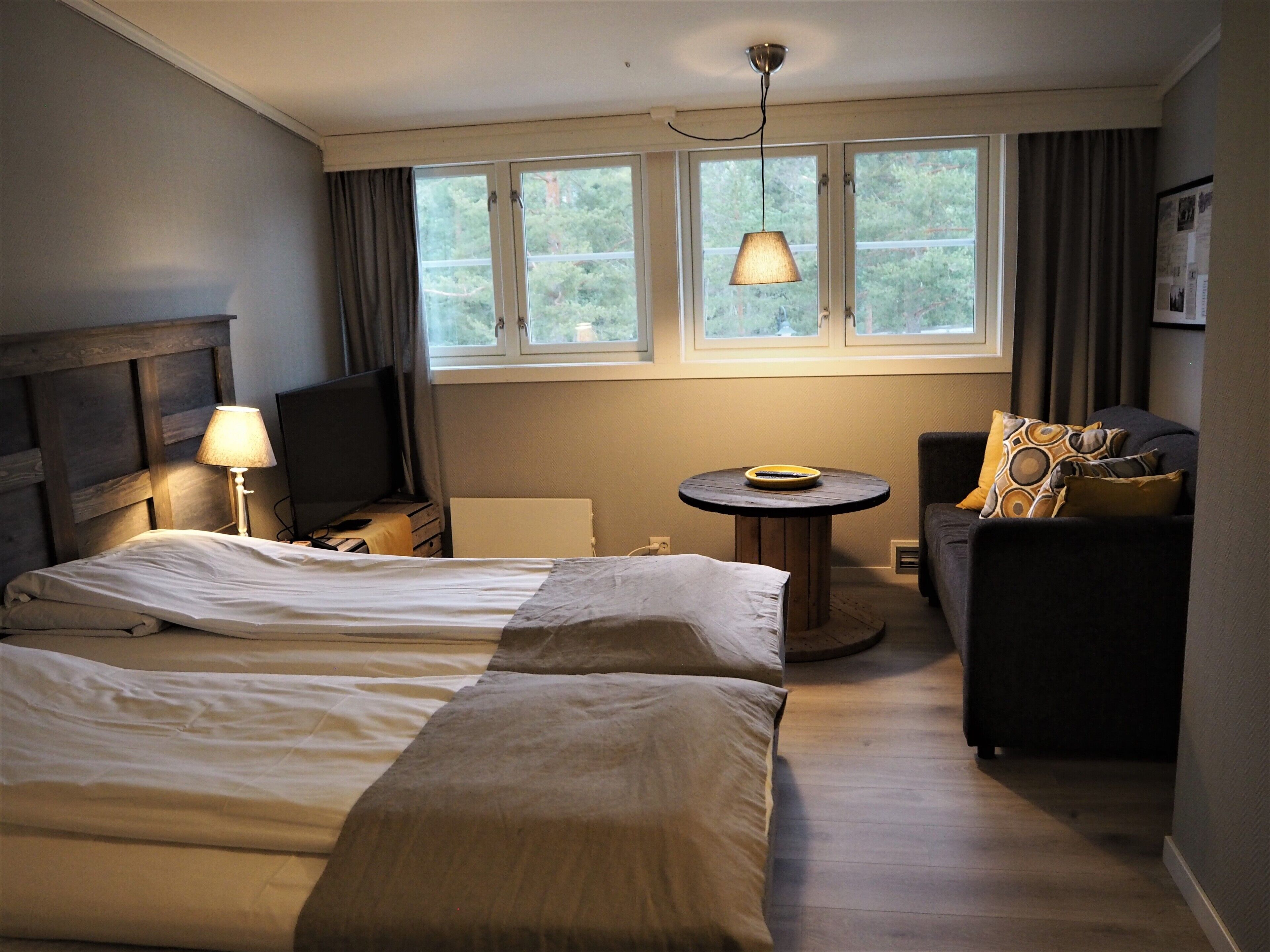 Een hotelkamer met twee bedden, een bureau, een stoel, een klein tafeltje en een raam met gordijnen.