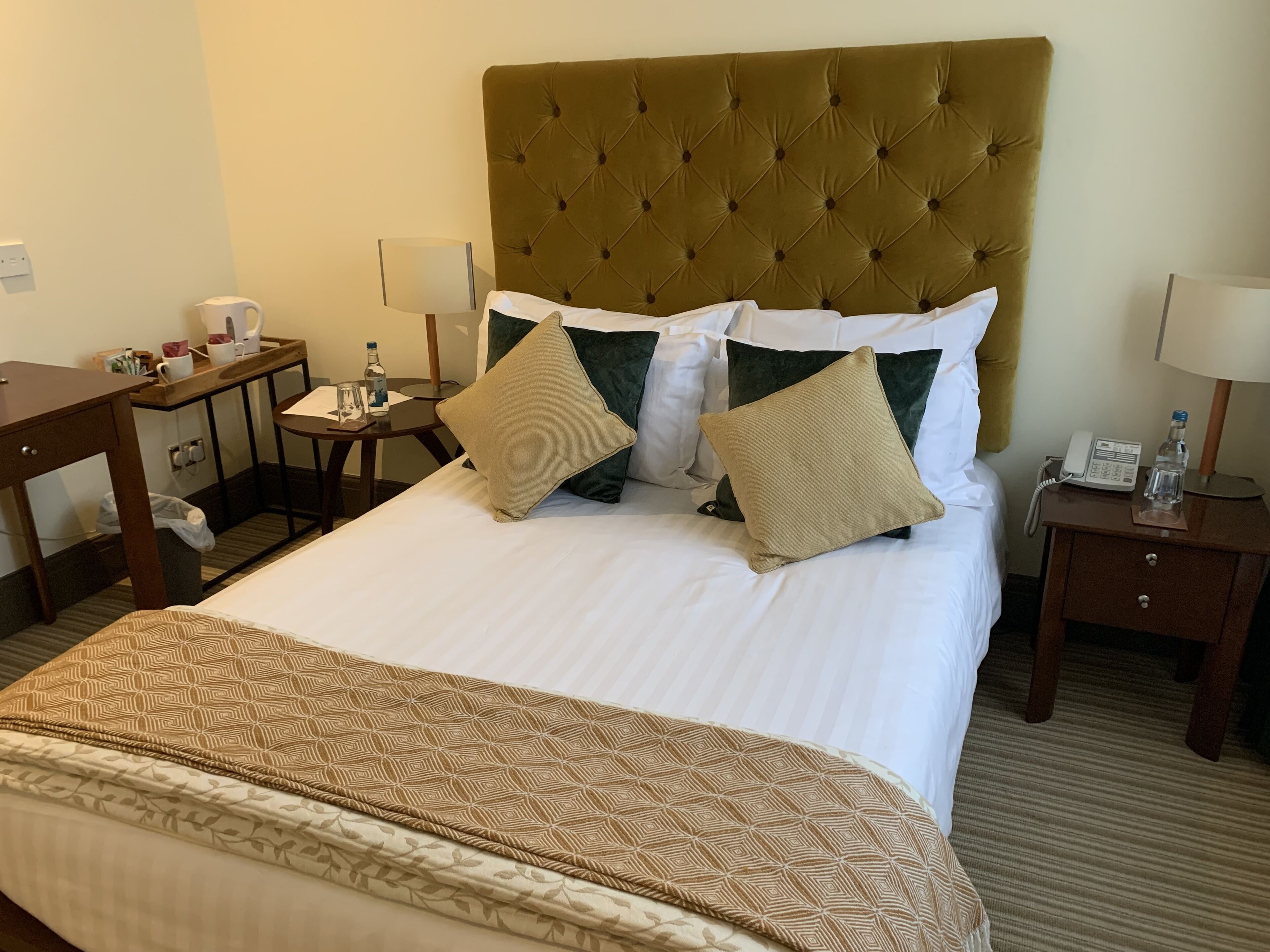 Una habitación de hotel con una cama grande, dos mesitas de noche, un escritorio y un teléfono.