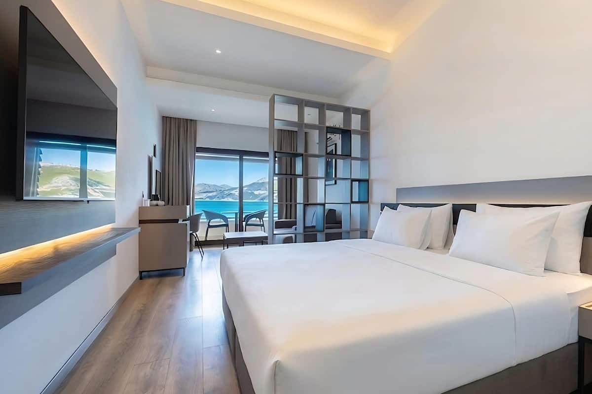 Une chambre d’hôtel moderne avec un grand lit, un bureau et une vue sur la mer.
