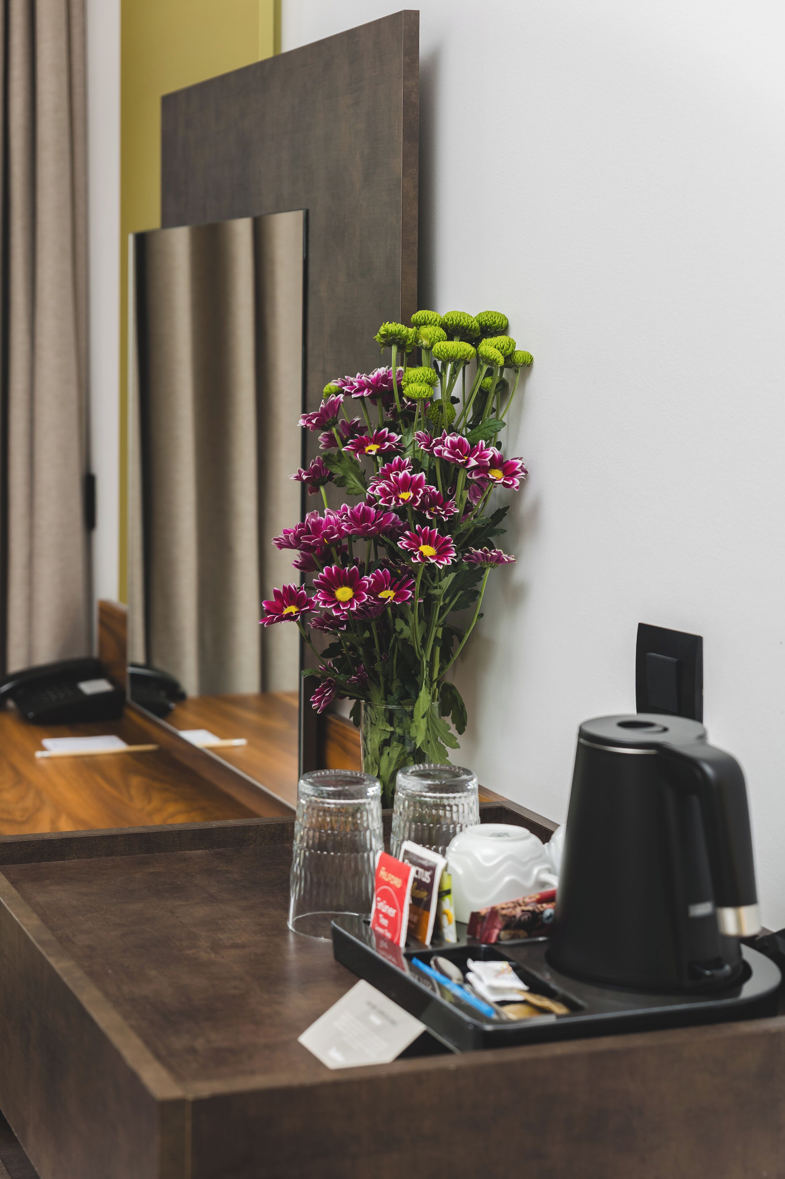 A reception desk with a vase of flowers, a coffee maker, and a telephone.