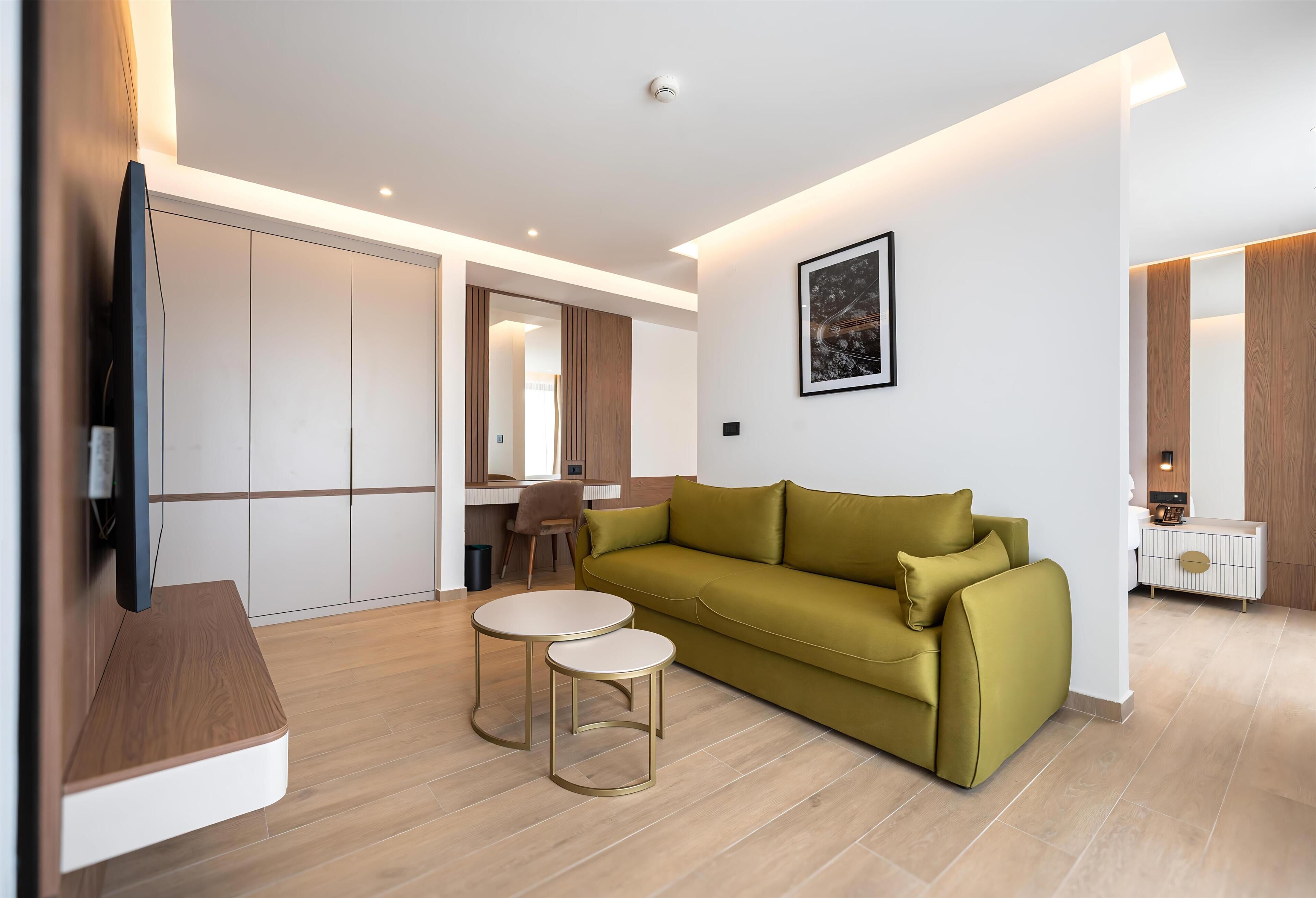 Een moderne woonkamer met een bank, twee bijzettafels, een flatscreen-tv en een ingelijste foto aan de muur.