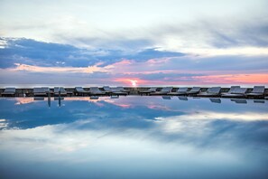 Ein Poolbereich mit Liegestühlen und Blick auf einen Sonnenuntergang.