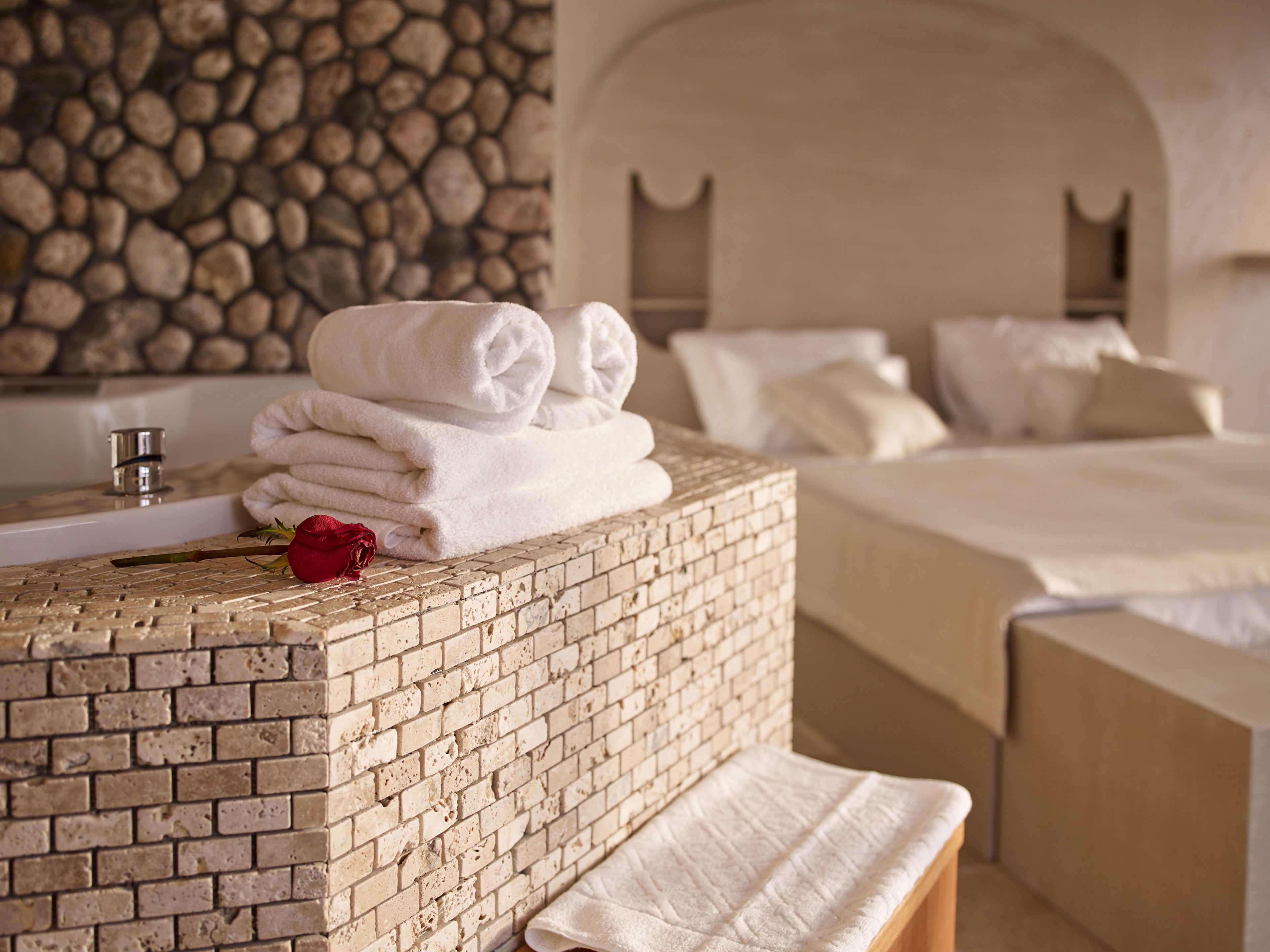 Ein Badezimmer mit Backsteinwand, Waschbecken und einem Bett mit weißer Bettwäsche.