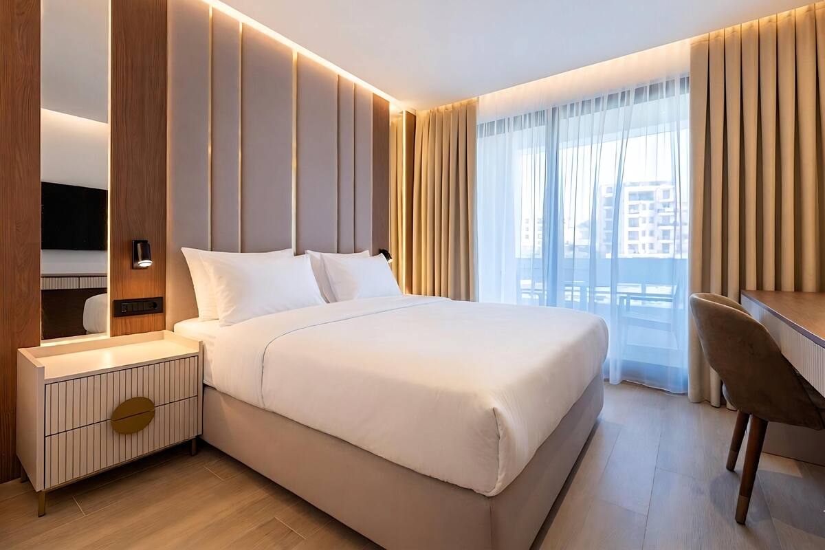 Une chambre d’hôtel moderne équipée d’un grand lit, d’un bureau, d’une chaise et d’un téléviseur.