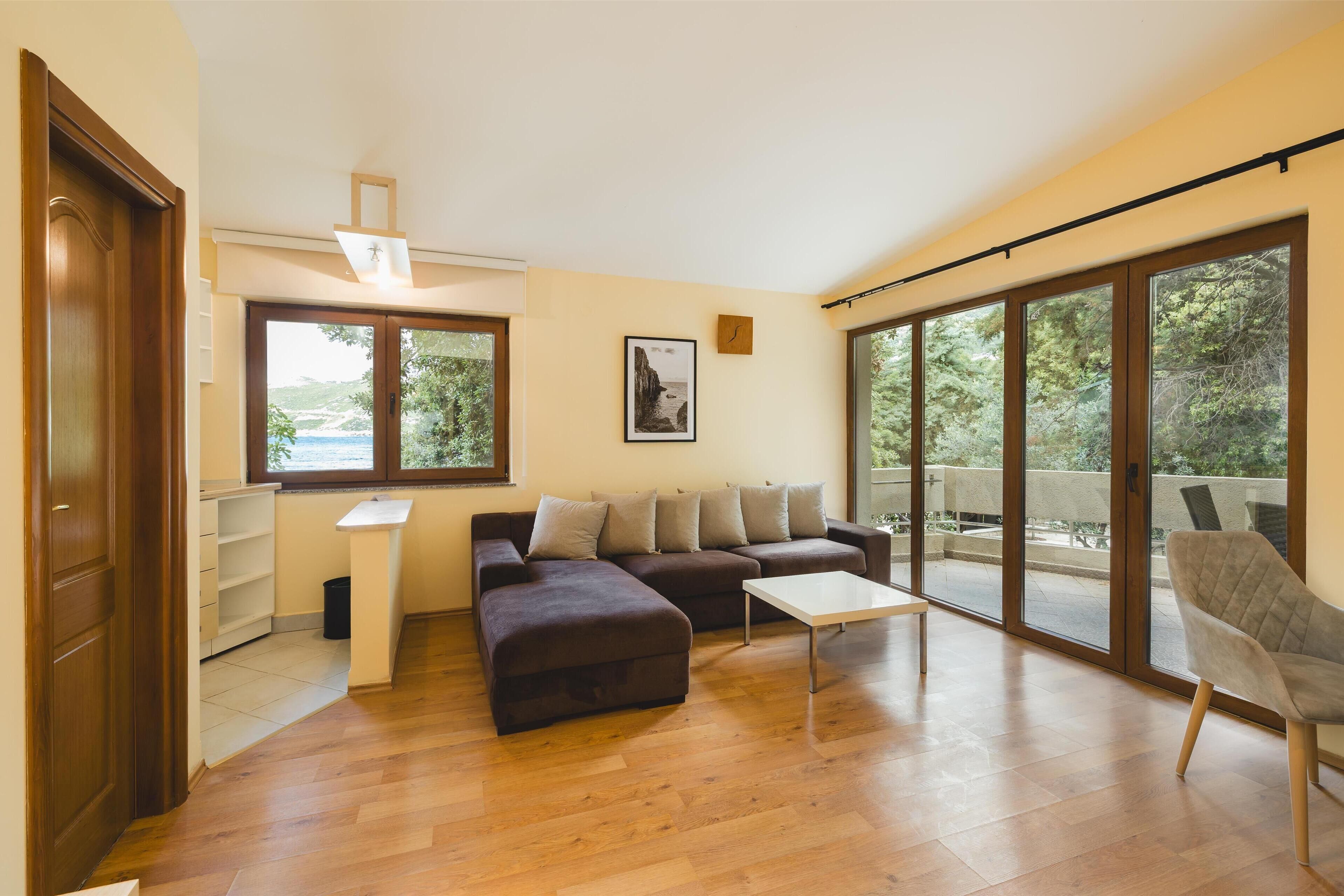 Ein modernes Wohnzimmer mit einer Eckcouch, einem Couchtisch und großen Schiebegläsern, die auf einen Balkon führen.