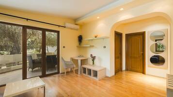 Un interior moderno con piso de madera, un ventanal corredero que da a un balcón, una pequeña mesa, una silla y un banco.