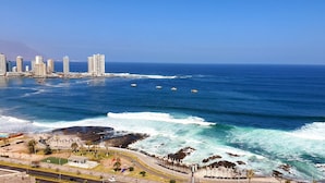 Un paisaje urbano costero con edificios altos, una playa y un paseo marítimo.