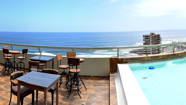 Una piscina en la azotea con vistas al océano y al horizonte de la ciudad.