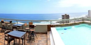 Una piscina en la azotea con vistas al océano y al horizonte de la ciudad.