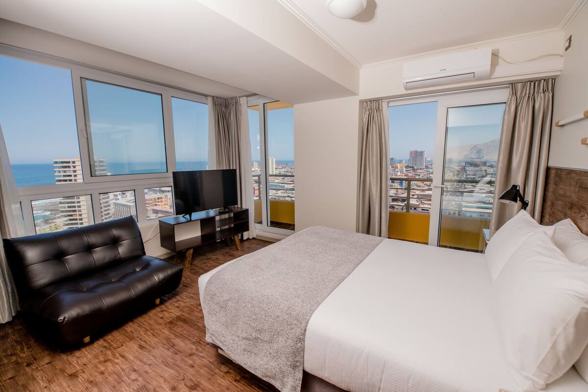 Una habitación de hotel con una cama grande, televisión, sofá y escritorio.