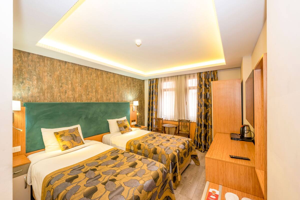 A hotel room with two beds, a desk, a chair, and a television.
