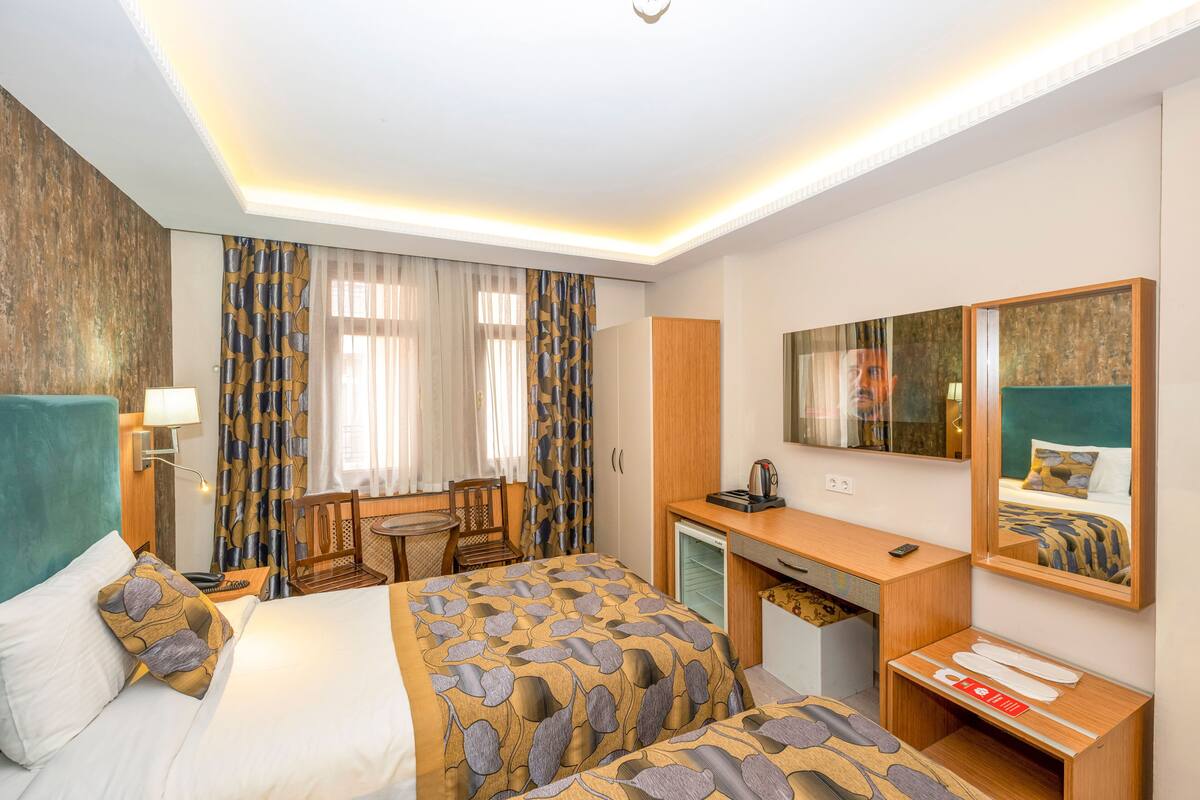 A hotel room with a bed, desk, chair, and a small kitchenette.