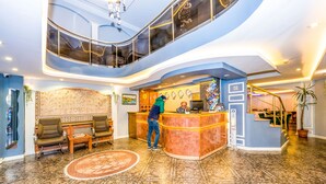 A lobby with a reception desk, seating area, and a staircase leading to an upper level. - Hotel Devman (Istanbul)