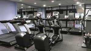 Un gimnasio con varias cintas de correr y máquinas elípticas.