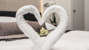 Una cama con un arreglo de toallas en forma de corazón y un ramo de rosas blancas.