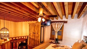 Una habitación acogedora con una cama, un escritorio, una silla, un ventilador de techo y una ventana con cortinas.