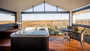 Een hottub op een houten terras met uitzicht op een wijngaard.