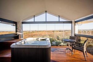 Un jacuzzi en una terraza de madera con vistas a un viñedo.