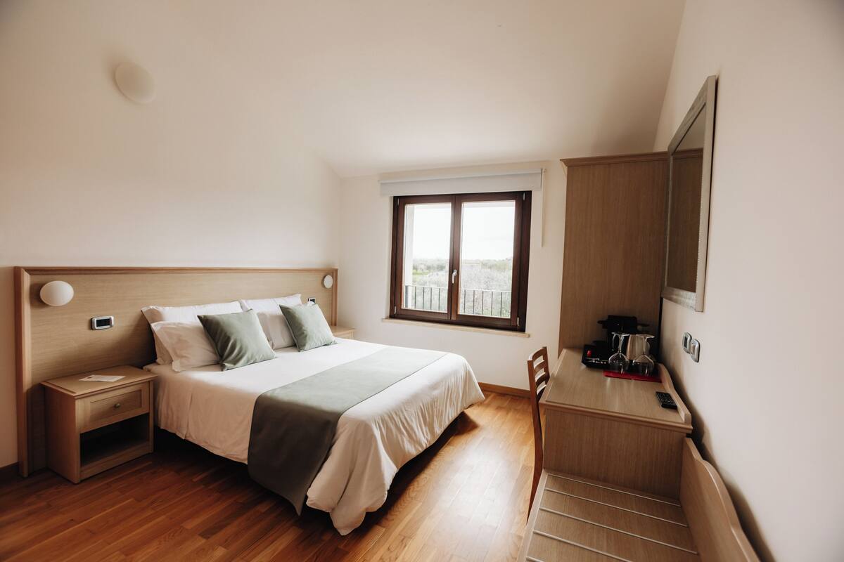 Un dormitorio con cama, mesita de noche, silla y ventana con vistas.
