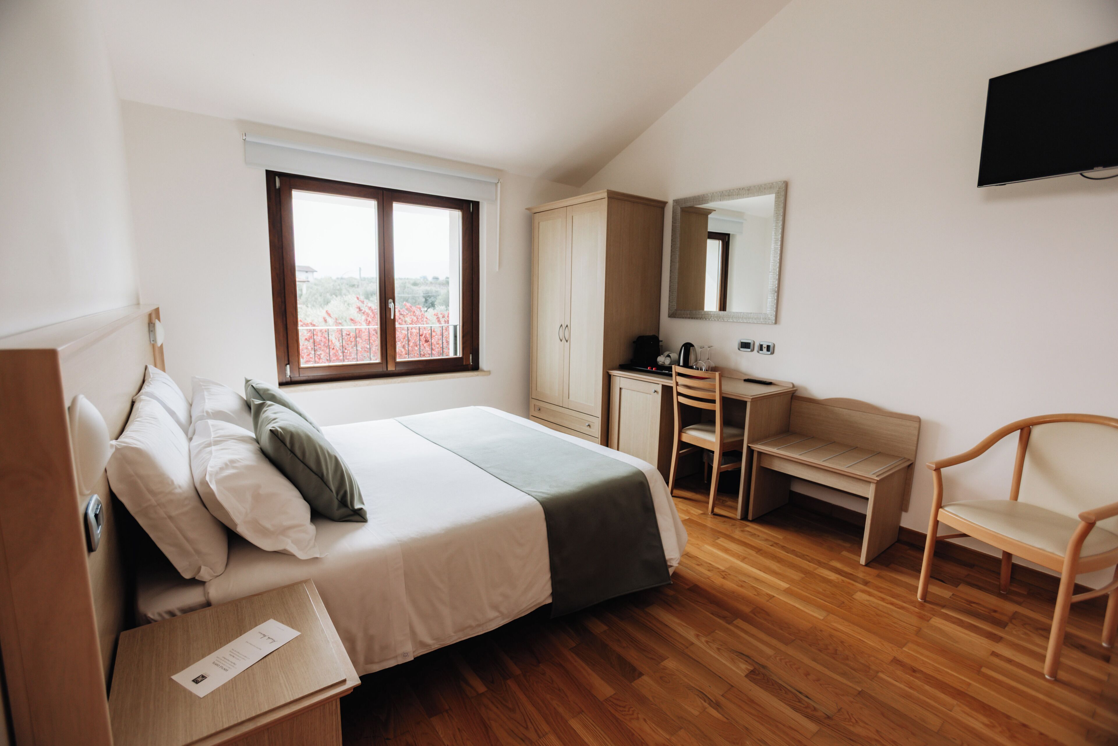 Ein Schlafzimmer mit einem Bett, einem Schreibtisch, einem Stuhl, einem Kleiderschrank und einem Fernseher an der Wand.