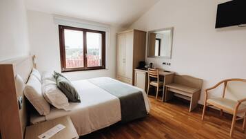 Ein Schlafzimmer mit einem Bett, einem Schreibtisch, einem Stuhl, einem Kleiderschrank und einem Fernseher an der Wand.