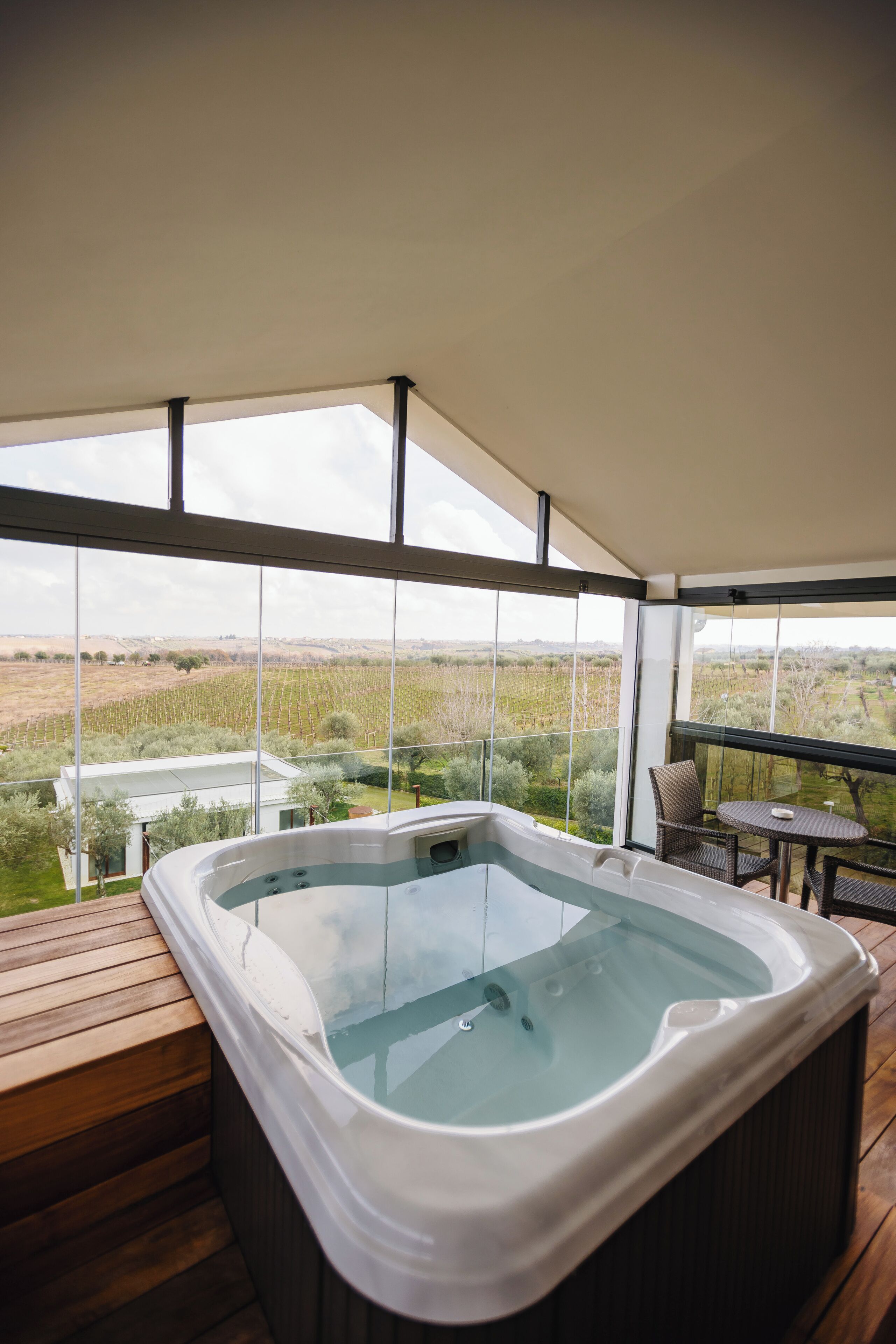 Ein Whirlpool auf einer Holzterrasse mit Blick auf einen Weinberg.