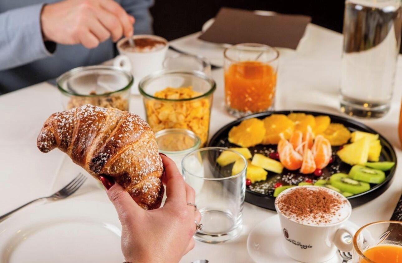 Colazione con croissant, frutta fresca, caffè e succo di frutta.