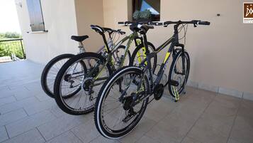 Deux vélos sont garés sur un balcon carrelé, avec en arrière-plan une vue sur la verdure.