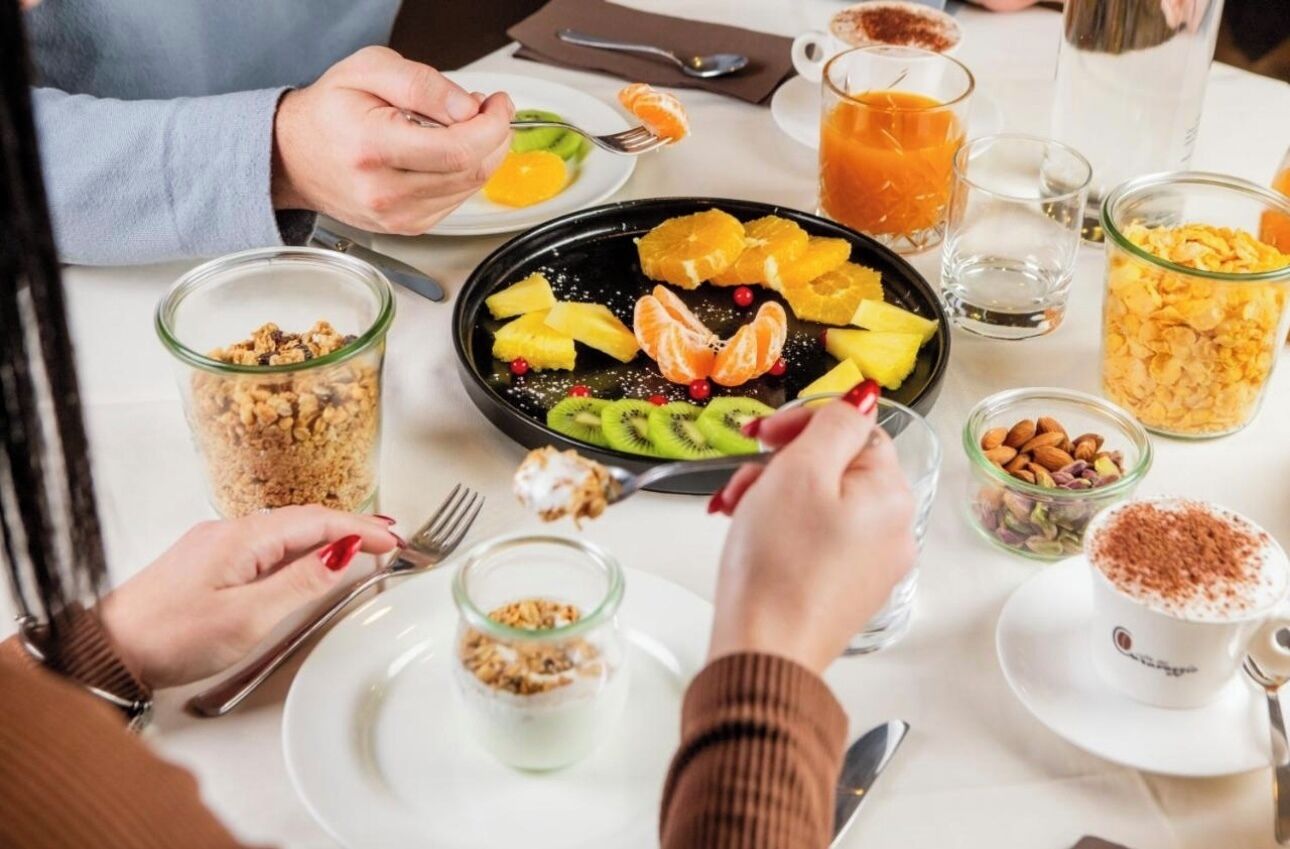 A breakfast setting with a variety of fruits, cereals, and beverages on a table.