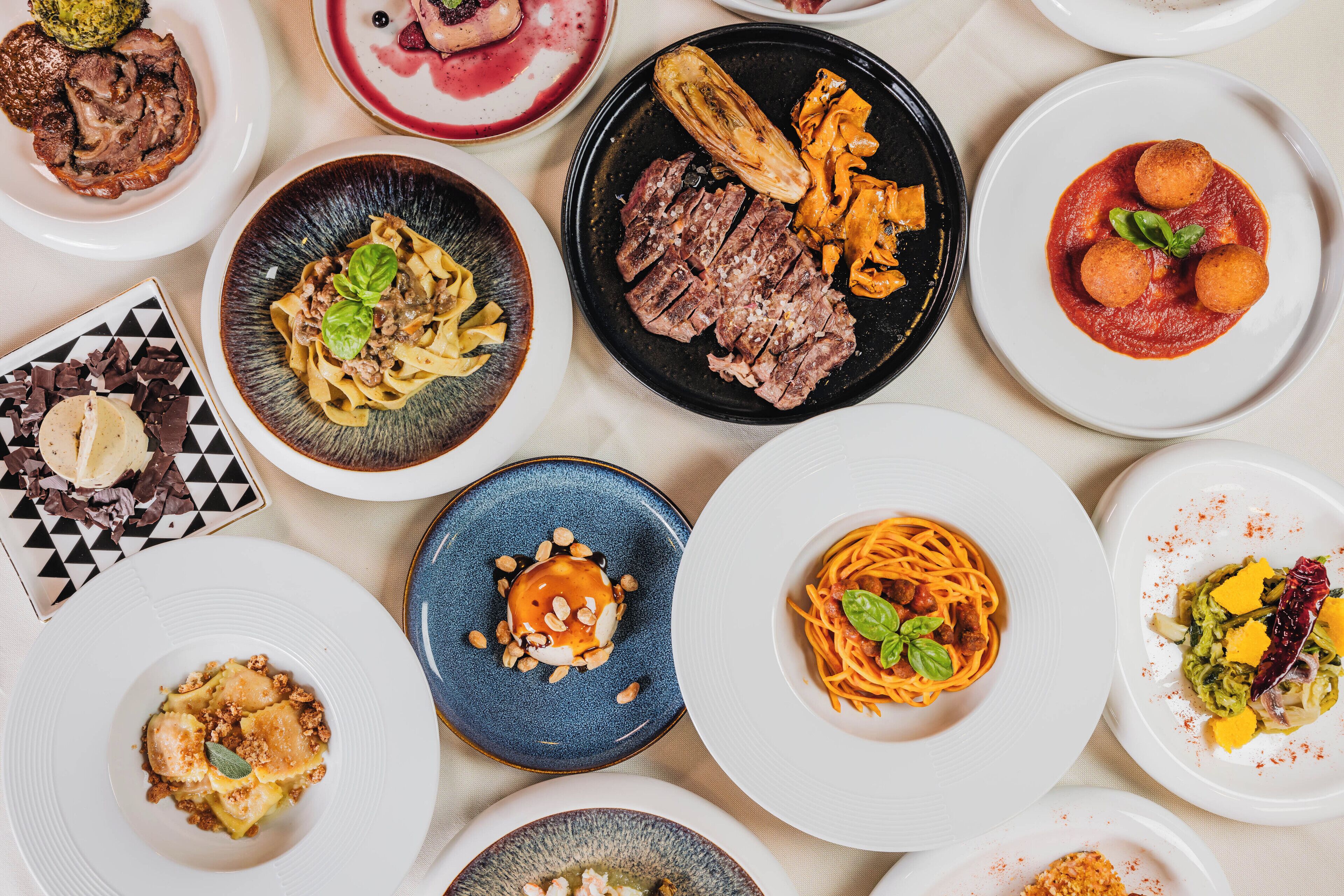 A variety of dishes on plates, including pasta, steak, and other entrees.