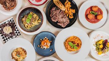 A variety of dishes on plates, including pasta, steak, and other entrees.