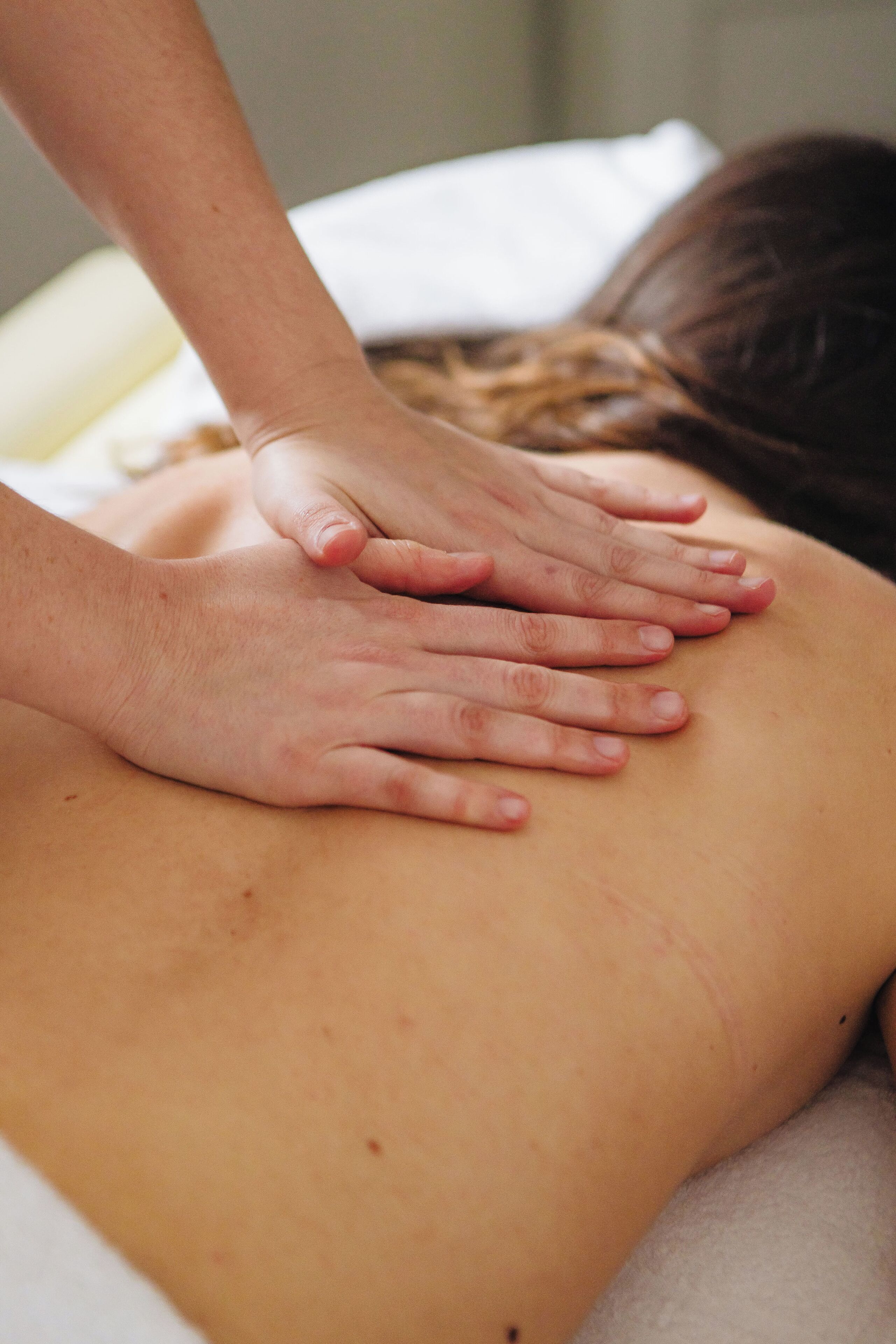 A massage therapy session with hands on a person's back.