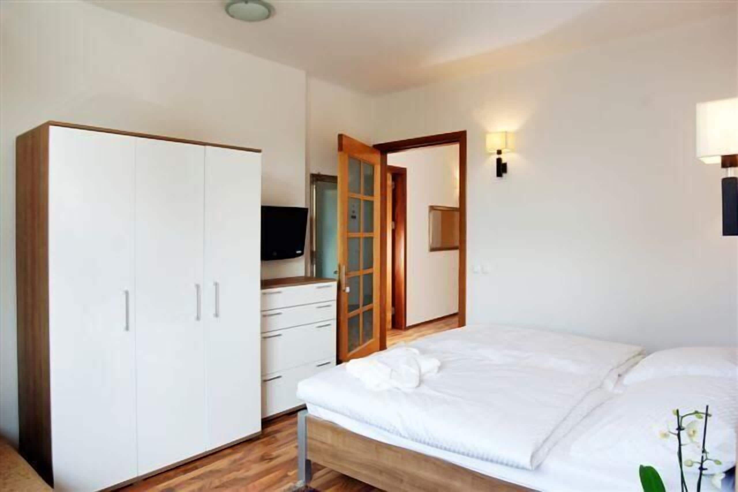 Un dormitorio con cama, armario, televisor y espejo.