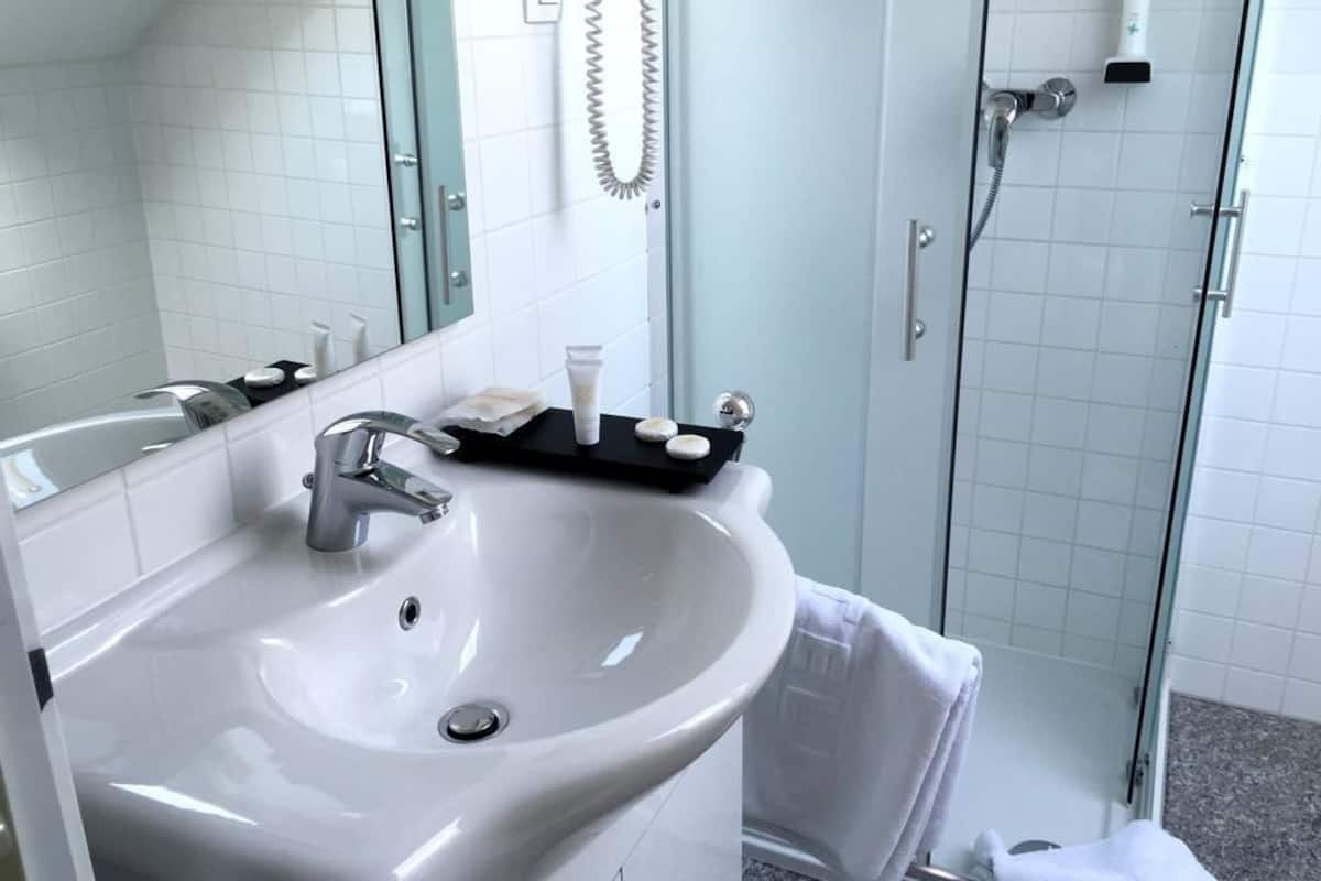 Een moderne badkamer met een wit wastafelmeubel, een spiegel en een douche met glazen wanden.