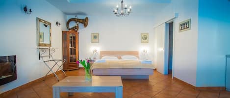 A bedroom with a bed, a wooden cabinet, a table, and a chandelier.