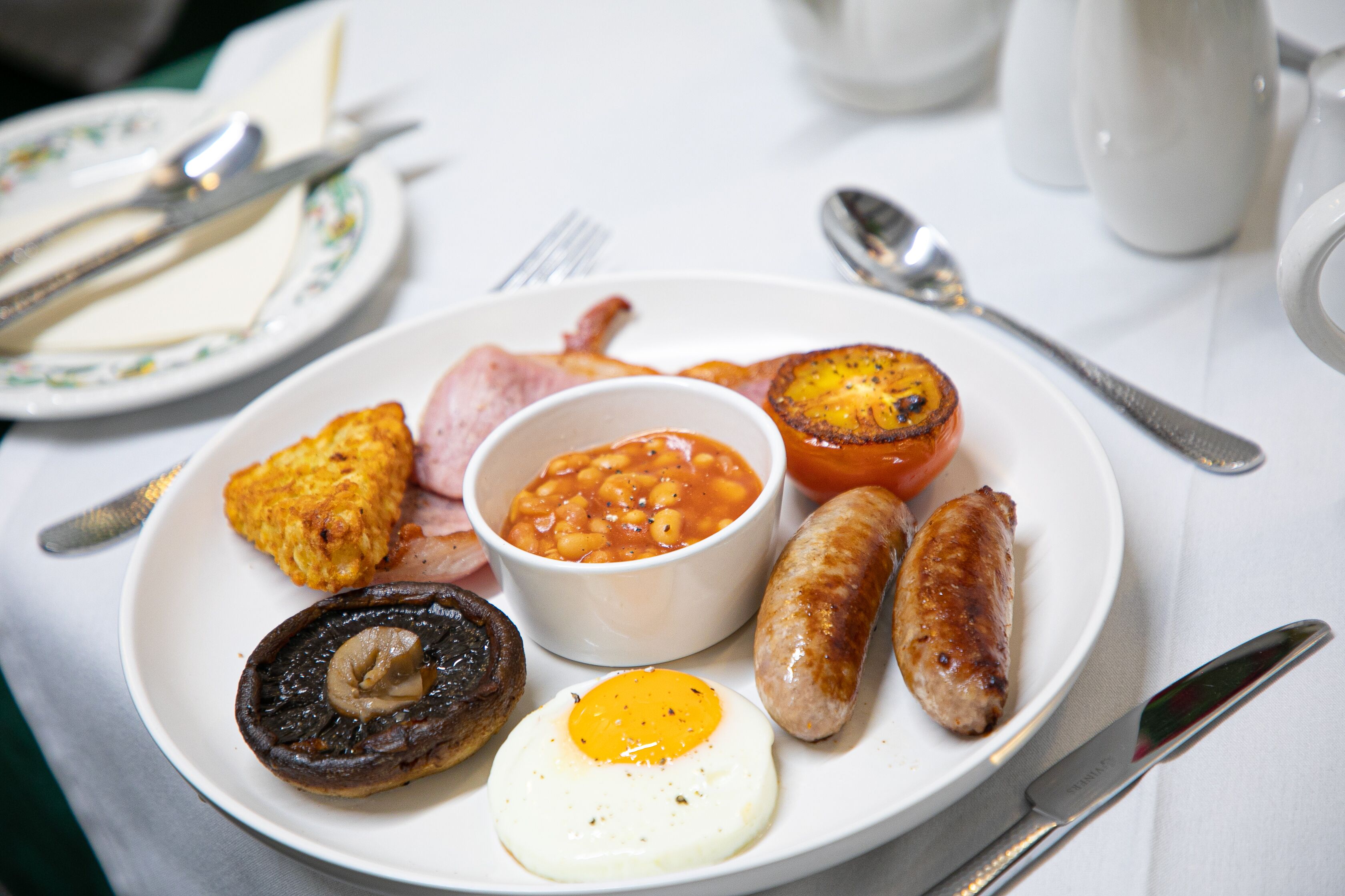 A plate of breakfast food including eggs, sausages, beans, and toast.