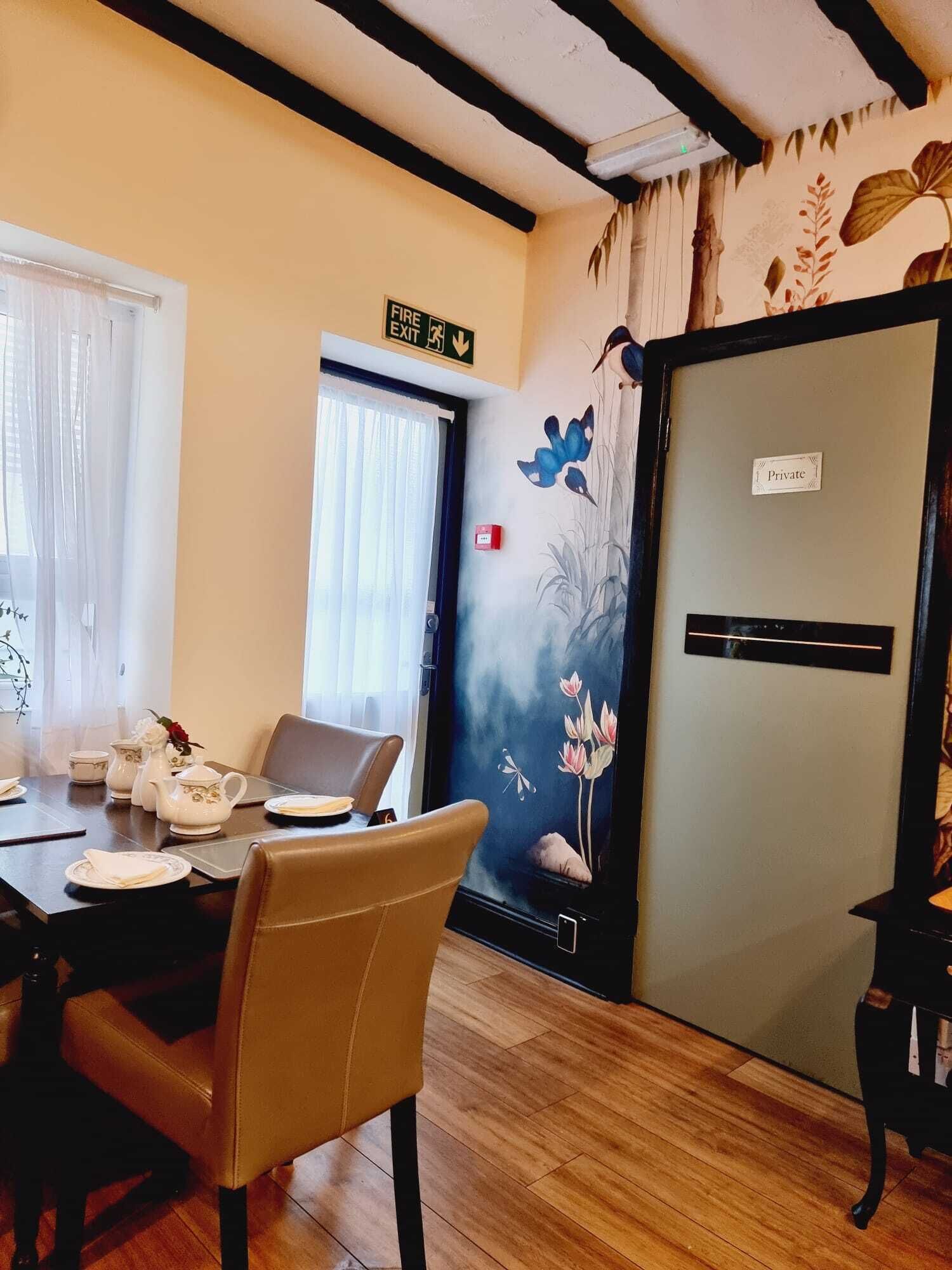 A dining area with a table set for two, a private room sign, and a door with a fire exit sign.