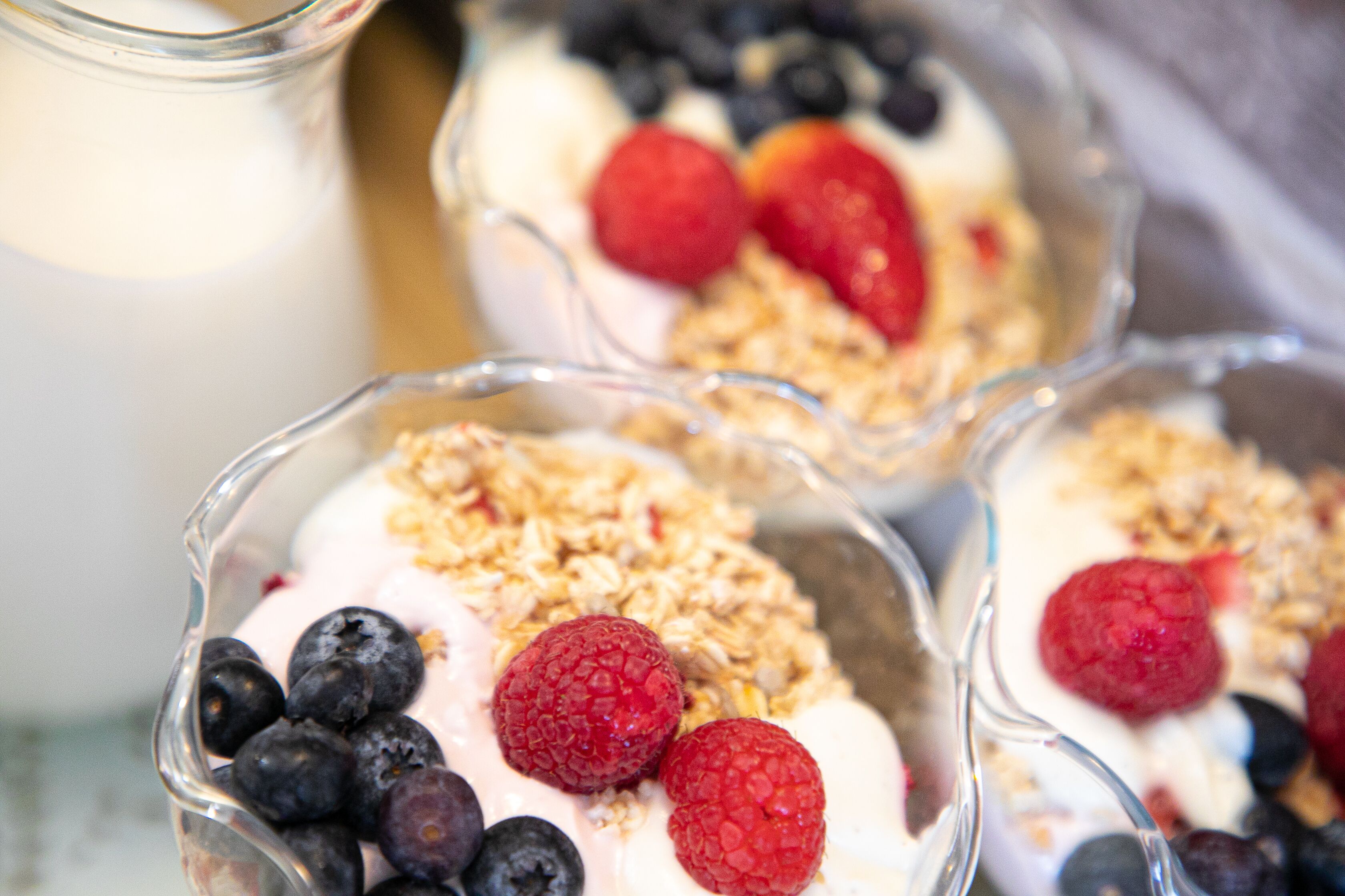 Three bowls of yogurt topped with granola and berries.